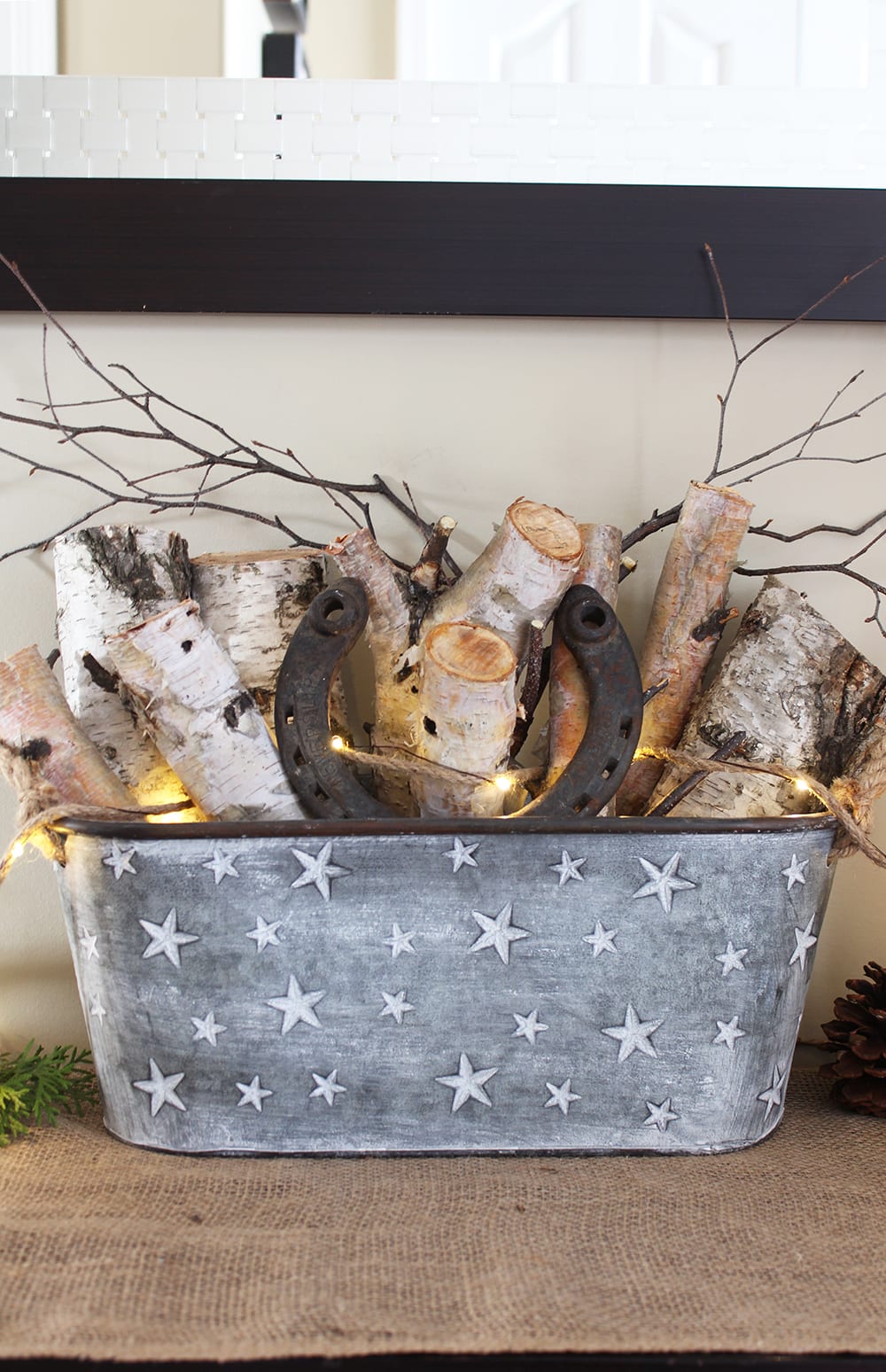 Nature inspired holiday decor featuring birch logs and twigs in a galvanized steel bucket, plus a horseshoe for good luck.