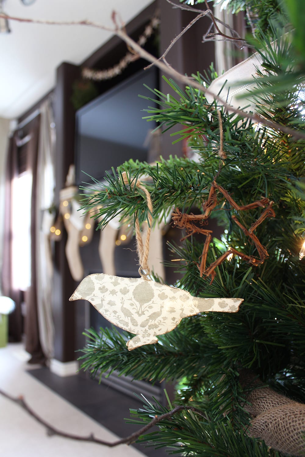 Nature inspired holiday decor featuring bird and star ornaments on a faux Christmas tree with real birch branches.
