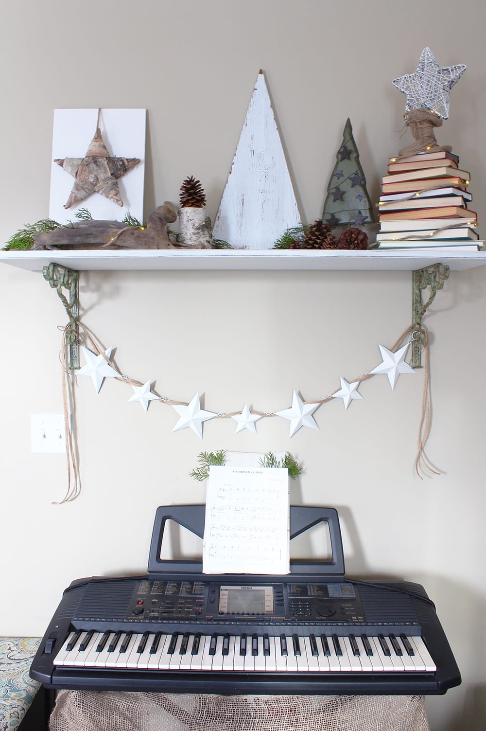 Nature inspired holiday decor featuring driftwood, a birch bark star and a Christmas tree made out of a stack of books.