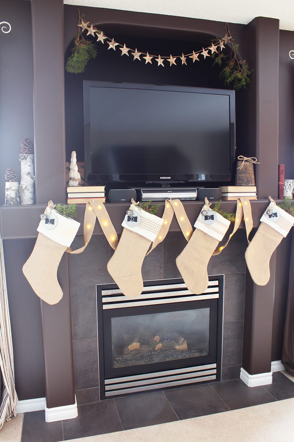 Nature inspired holiday decor featuring burlap stockings, birch logs, a star garland and fresh greenery.