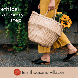 A person walking holding a basket of flowers. Click here to visit Ten Thousand Villages.