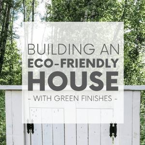 A white wooden vanity in front of a green forest with the words "building an eco-friendly house - with green finishes." Click to visit post.