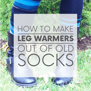 A closeup of a pair of legs wearing blue and black striped leg warmers standing in front of a tree with the words "how to make leg warmers out of old socks." Click to visit post.