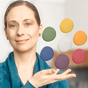 A closeup of Larissa wearing a blue sweater and holding her hand out with colourful paint swatches floating above.