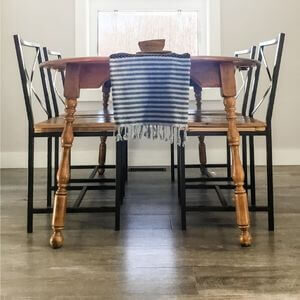 A wooden table with four metal and wood chairs in front of a window.