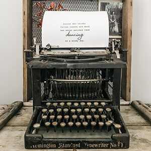 A antique typewriter sitting on an old wooden box.