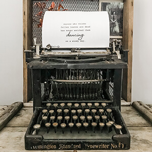 A antique typewriter sitting on an old wooden box.