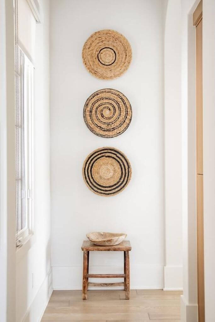 Three patterned baskets hanging over a small stool.