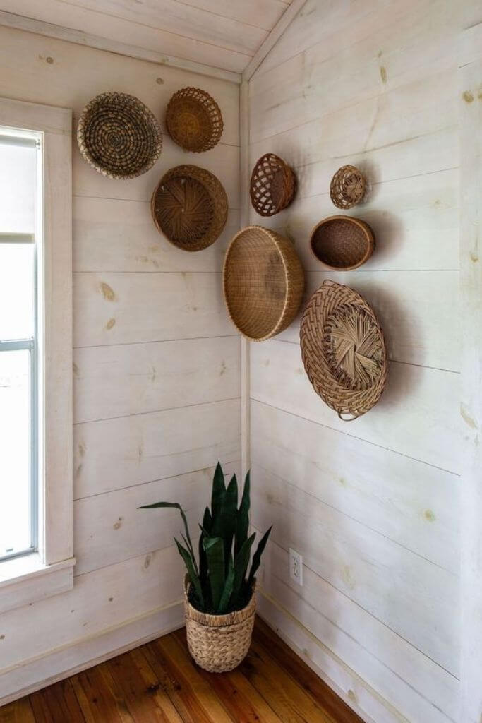 Various brown baskets hanging on a whitewashed wood wall.