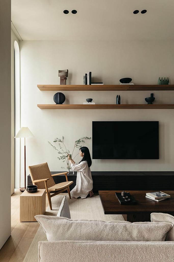 A woman arranging flowers in a vase in a Japandi inspired living room.
