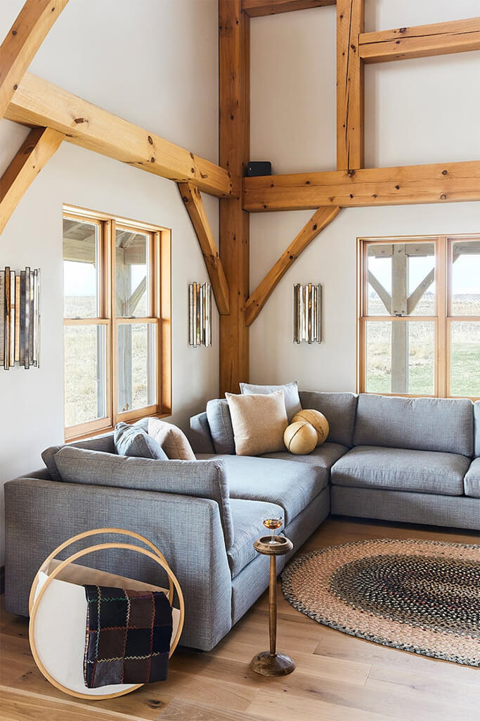 A living room with exposed wood posts and beams and large windows.
