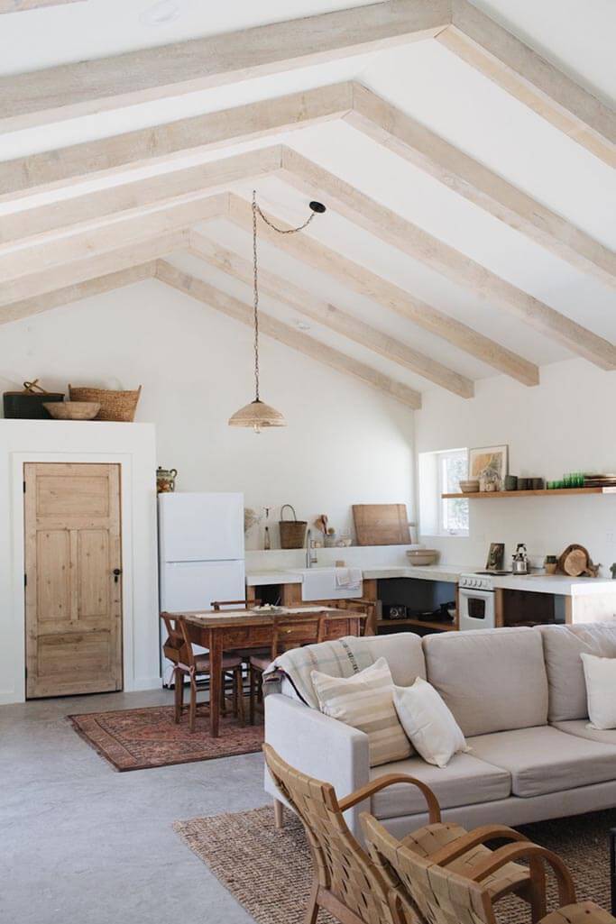 A dining room and kitchen with higgh ceilings and rustic finishes.