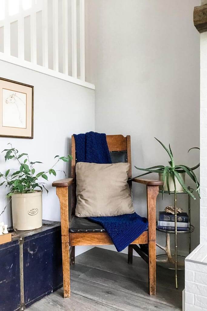 An old chair next to a vintage brass table and blue metal chest.