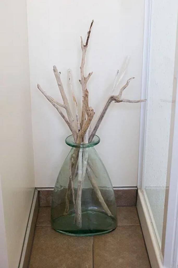 A blue glass vase with driftwood twigs inside.