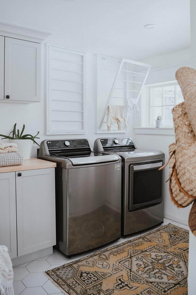 A laundry room with a patterned rug and a grey washer and dryer.