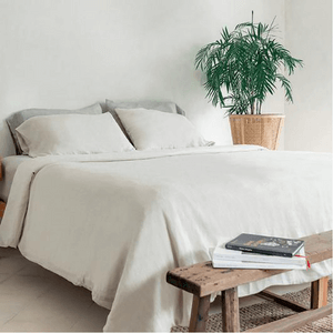 A bedroom with neutral coloured bedding.