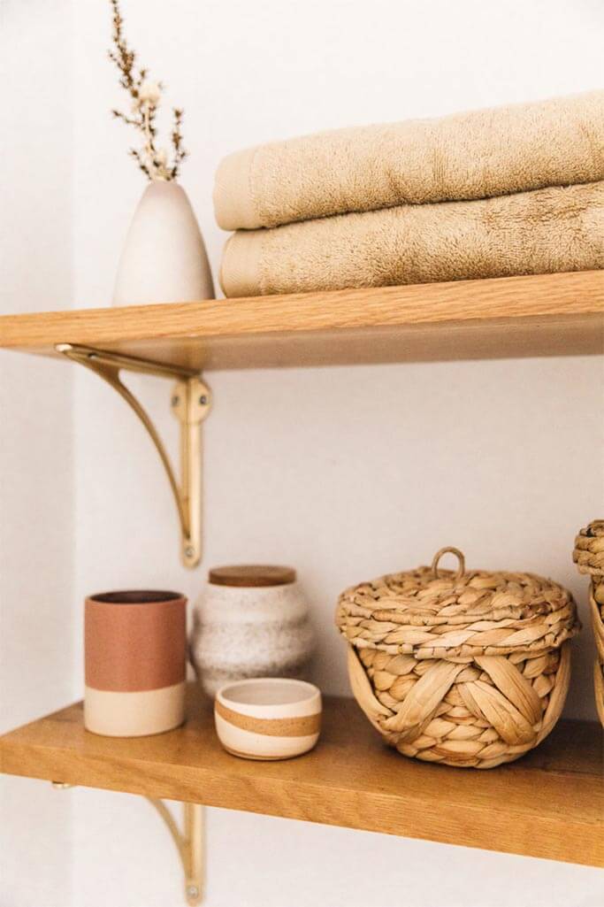 Beige bath towels on a wooden shelf.