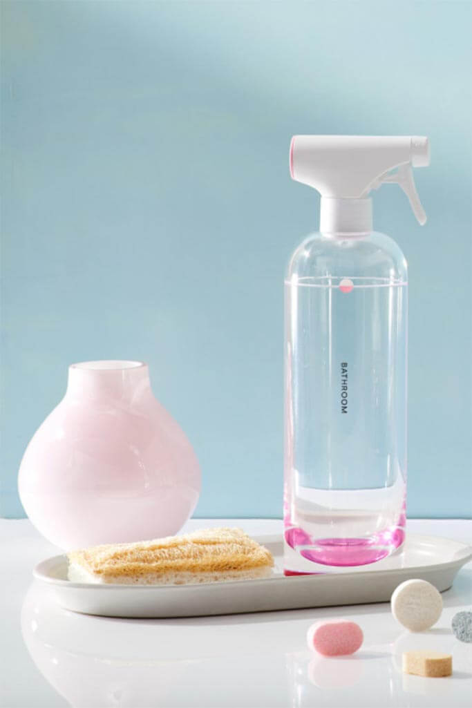 A glass bottle next to a pink vase and a blue background.