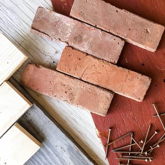 Various reclaimed building materials such as red bricks, screws and 2x4s.