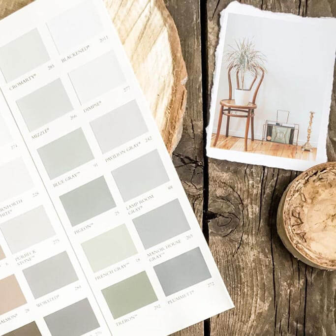 A paint sample booklet on a rustic wood background next to a photo of a wooden chair.