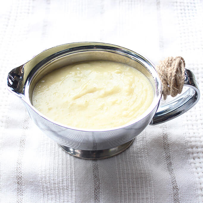Light brown gravy in a silver gravy boat.
