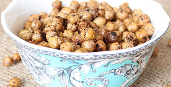A blue bowl with a floral pattern filled with baked chickpeas.