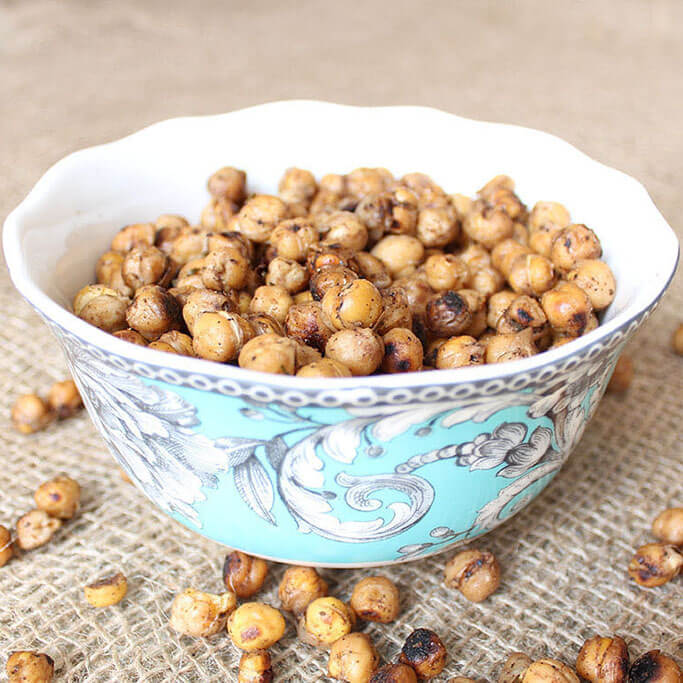 A blue bowl with a floral pattern filled with baked chickpeas.
