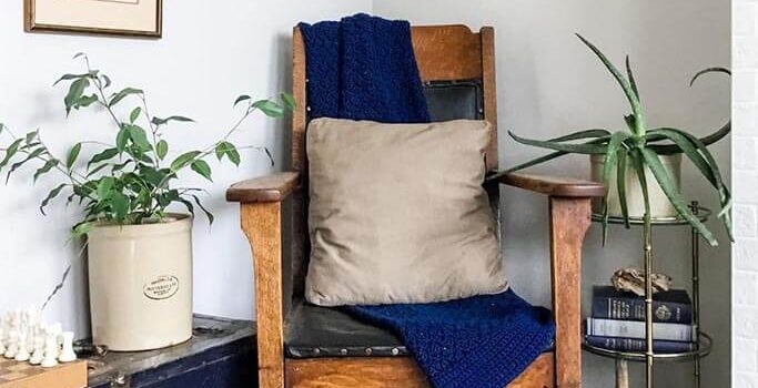A wooden chair sitting in a corner with dark blue and gold accents.
