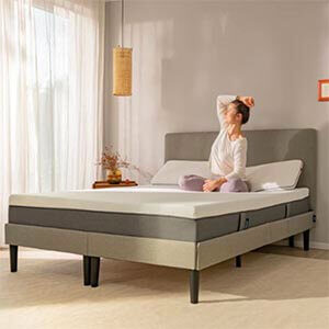 A woman sitting on a bed and stretching.