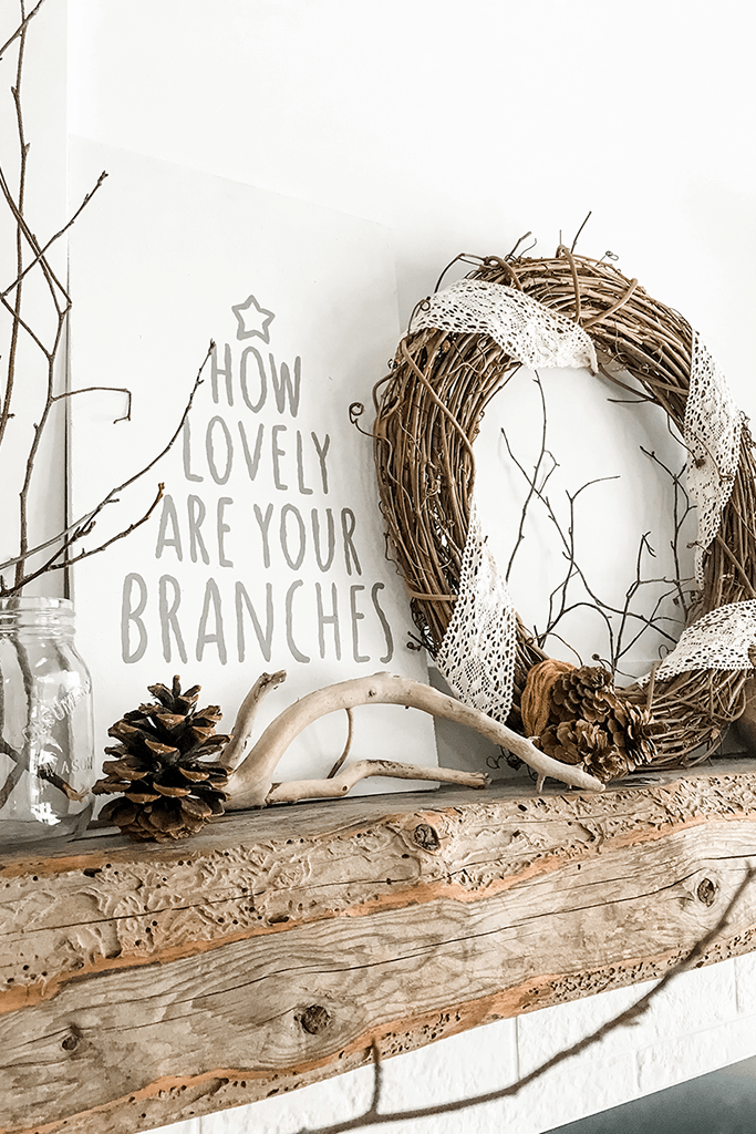 A wooden mantel with a white sign painted with the words how lovely are your branches.
