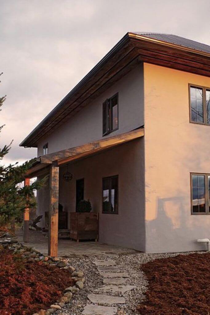 Exterior of an off-white straw bale farmhouse.