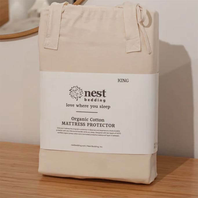 A mattress protector in a cotton bag with text printed on a label.