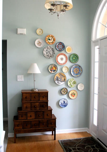A foyer with a dark wooden table and colourful plates hanging on the wall.