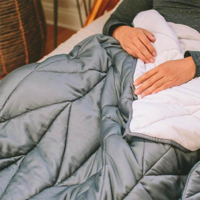 A blue-grey comforter draped over a person's lap.