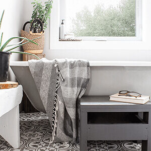 A grey and white bathroom with a clawfoot tub and plants.