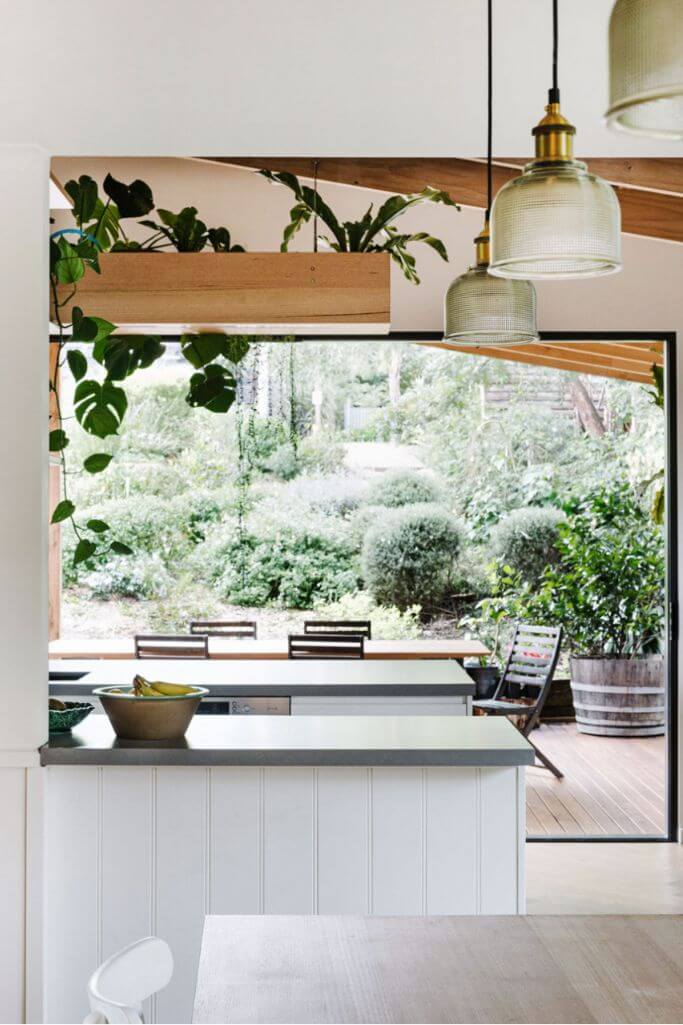 A white kitchen with a huge window and wood accents.