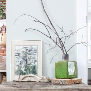 A rustic side table with nature-inspired artwork and decor on top.