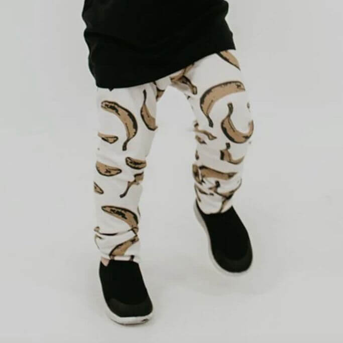 A child wearing leggings with bananas on them and a black tee.