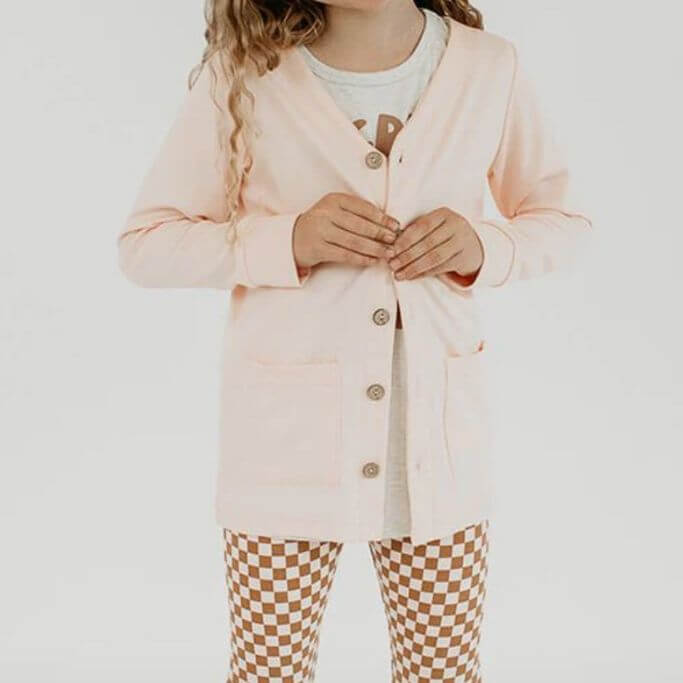 A child wearing a pink cardigan and checkered leggings.