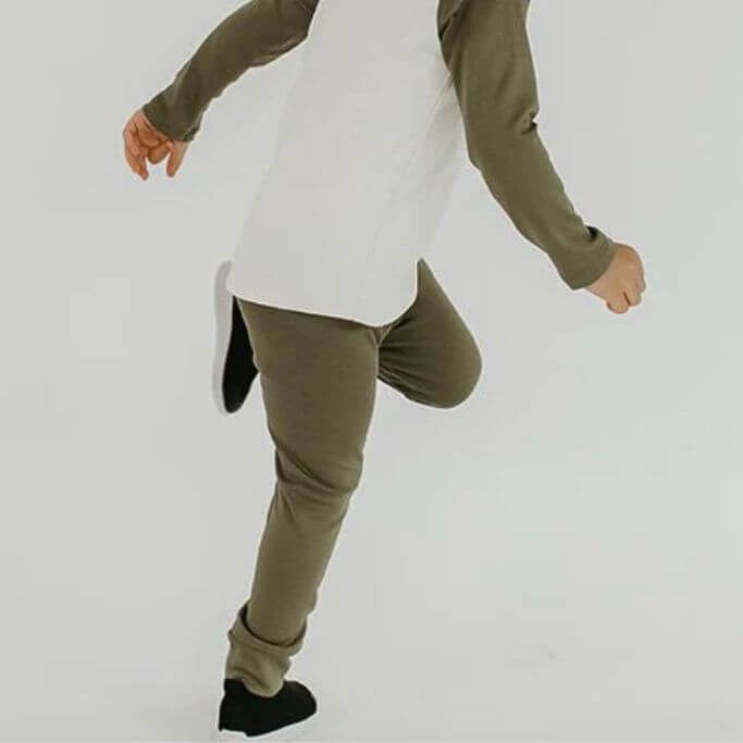 A child wearing olive green leggings and a white and green tee.