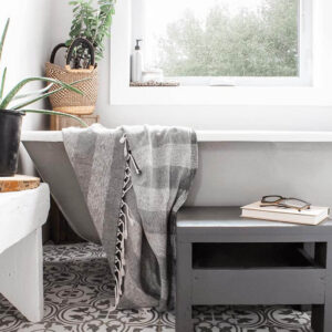 A grey and white farmhouse-style bathroom with a clawfoot tub and plants.
