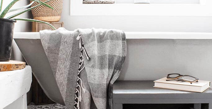 A grey and white farmhouse-style bathroom with a clawfoot tub and plants.