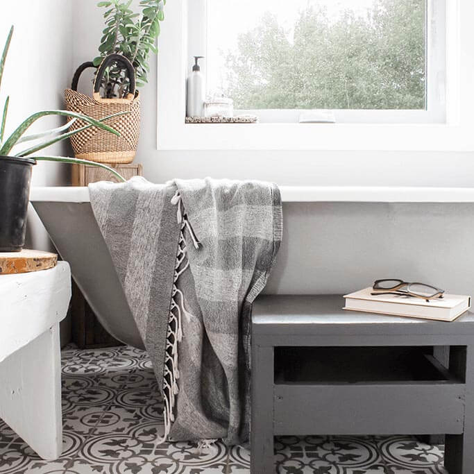 A grey and white farmhouse-style bathroom with a clawfoot tub and plants.