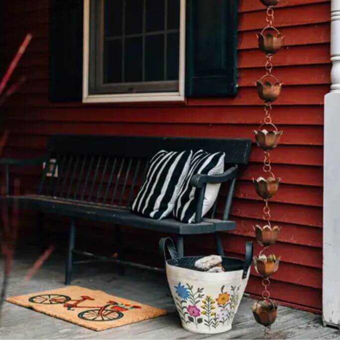 A front porch with a black sofa and a floral patterned basket.
