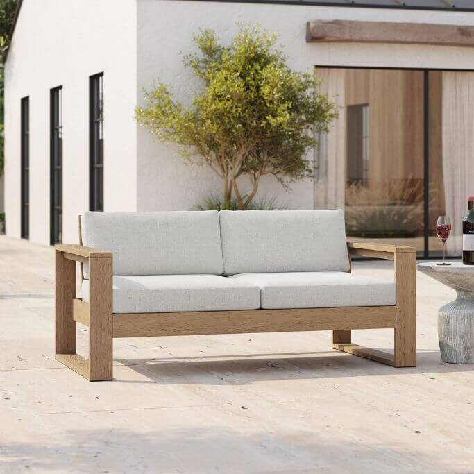 An outdoor sofa sitting in front of a beautiful white stucco home.