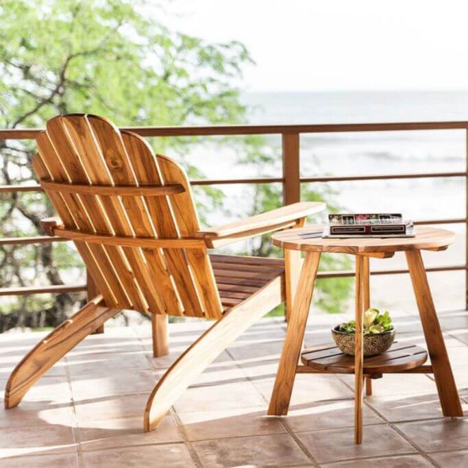 A wood adirondack chair and table looking out over the water.