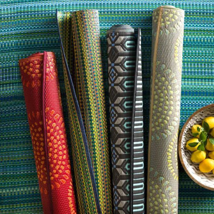 Four rolled up colourful rugs.