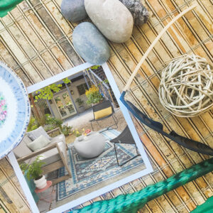 A photo of a beautiful backyard patio sitting next to sunglasses, rocks and a floral plate.