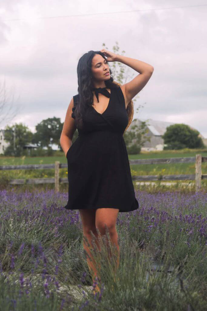 A woman wearing a black dress in a field of flowers.