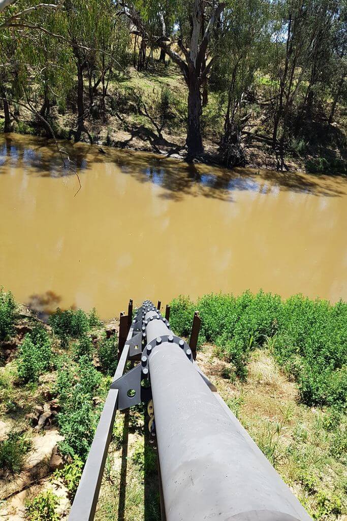A pipe pumping water out of a river.